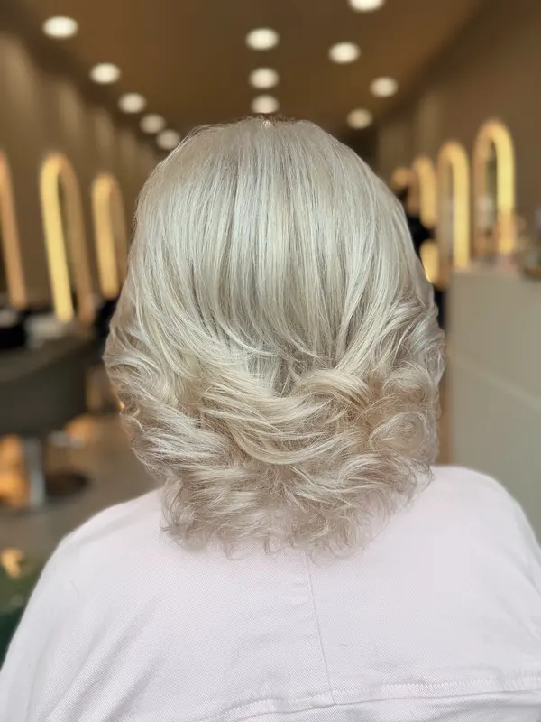 Licht blond haar, ruim geföhnd met krullen in de punten